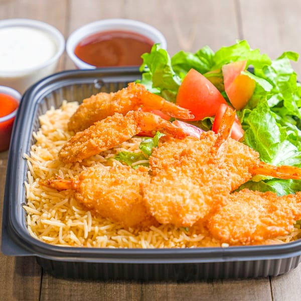 Halal fried shrimp and rice with a side salad in a black takeout container, with sauces.
