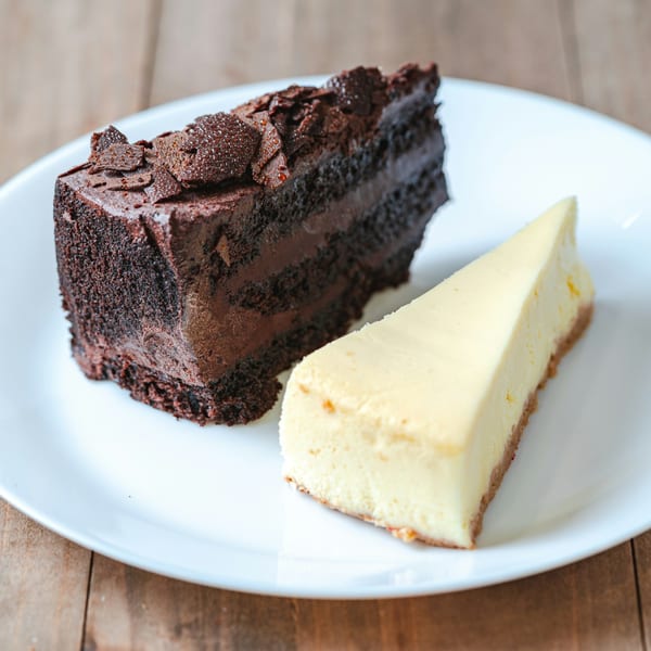 A slice of rich chocolate cake and a slice of creamy cheesecake on a white plate.