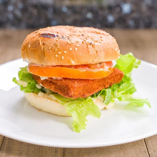 Halal crispy chicken sandwich with lettuce, tomato, and sauce on a sesame bun.